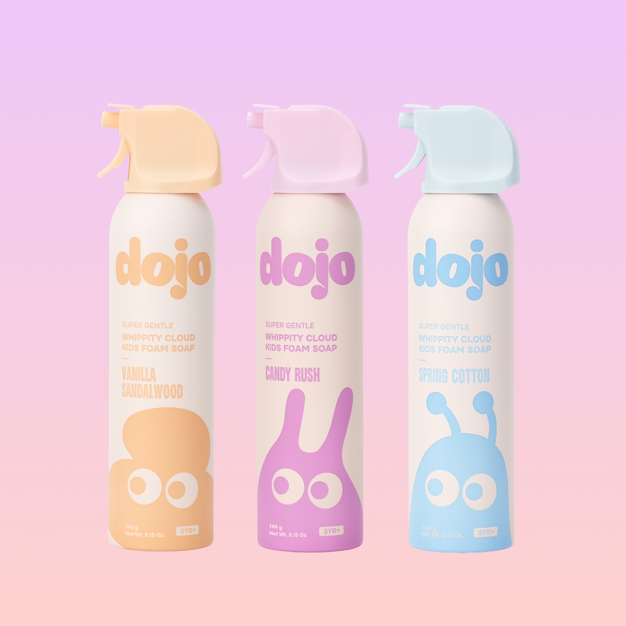 Three spray bottles of dojo Kid Foam Cloud KIDS FOAM SOAP arranged side by side on a pastel pink and lavender gradient background. The bottles are cream-colored with colorful labels and trigger sprayers.